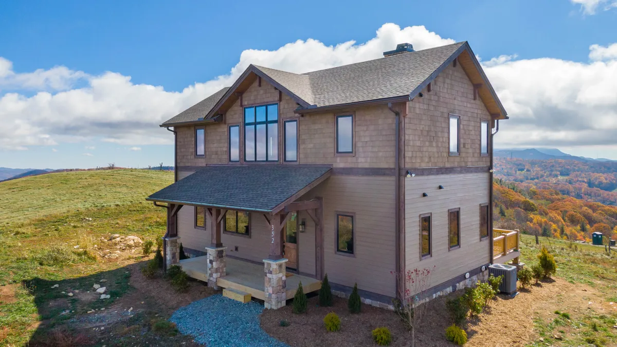 A welcoming view of the home's front porch and large windows, surrounded by natural beauty. The image captures a space designed for enjoying sunsets, stargazing, or gathering with family before heading out for local excursions.