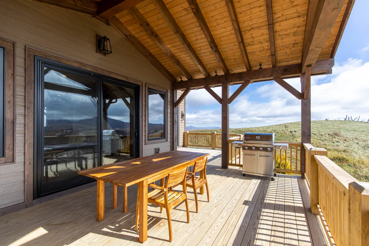 An outdoor dining space featuring a wooden table, grill, and sweeping scenic views. The setting hints at sunset dinners, barbecues, and relaxed family time after a day of exploring nearby attractions.