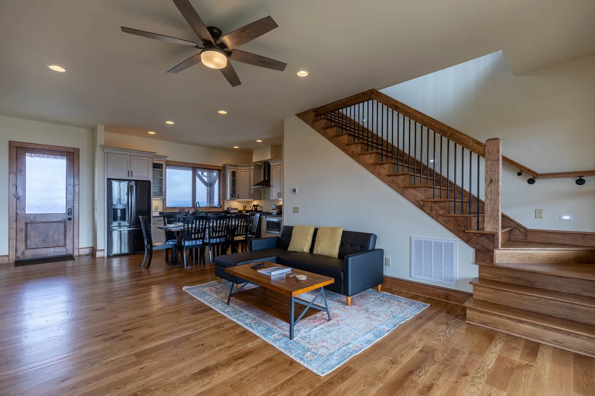A welcoming living area featuring a comfortable sofa, a dining table, a visible staircase, and a sturdy wooden door. The space is arranged for family gatherings and casual relaxation, with a cozy atmosphere that hints at easy access to the outdoors through the prominent entryway.